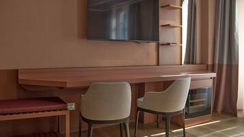 Quarto moderno com televisão de tela plana na parede, duas cadeiras, uma mesa pequena e lareira embutida.