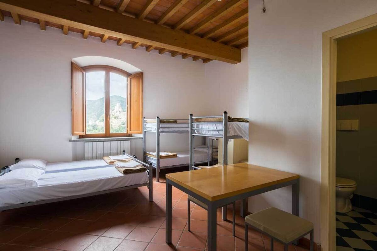 A room with bunk beds, a table, and a window with a view.