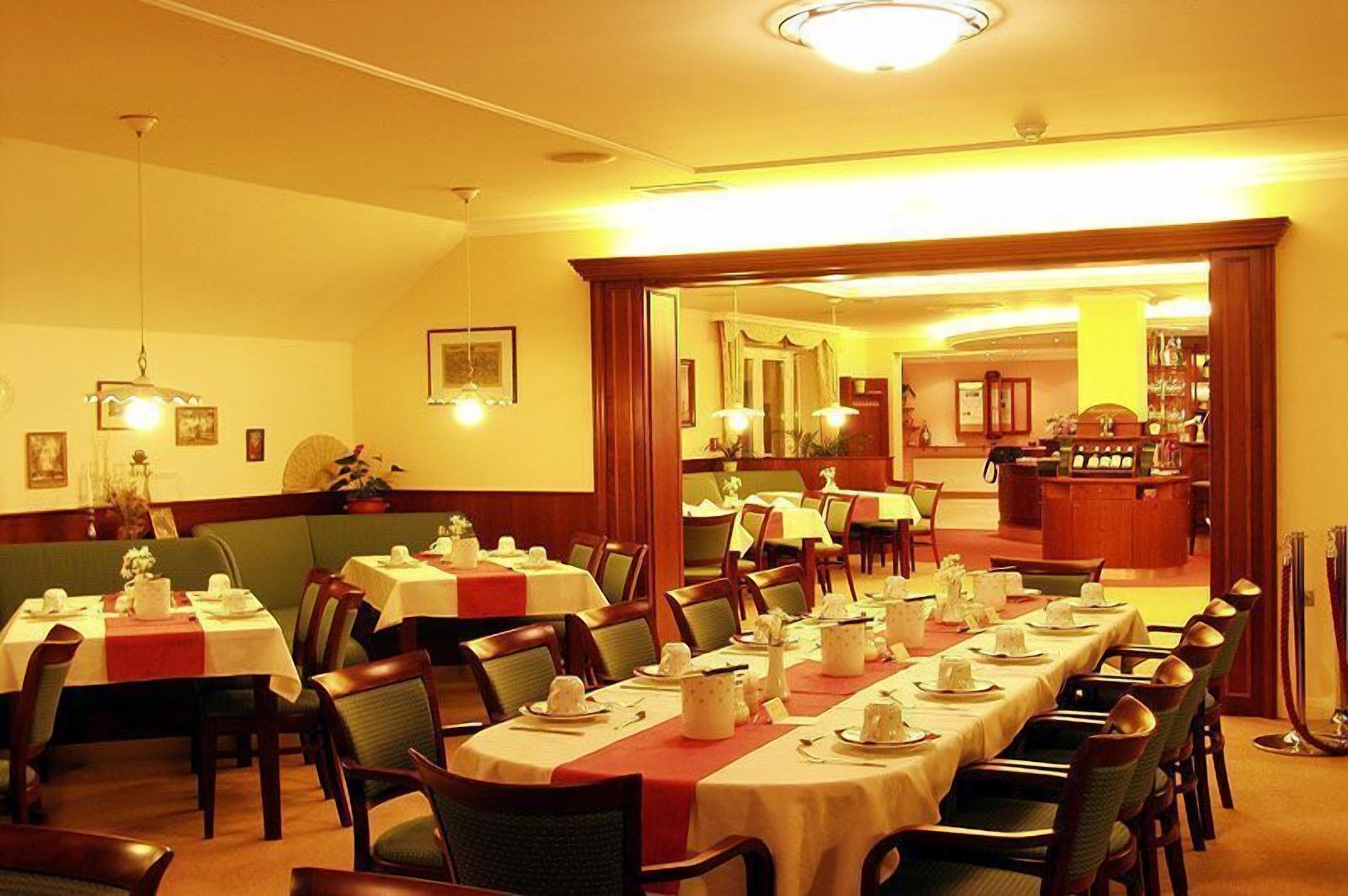 Un restaurant avec plusieurs tables dressées pour le service, un bar et un comptoir.