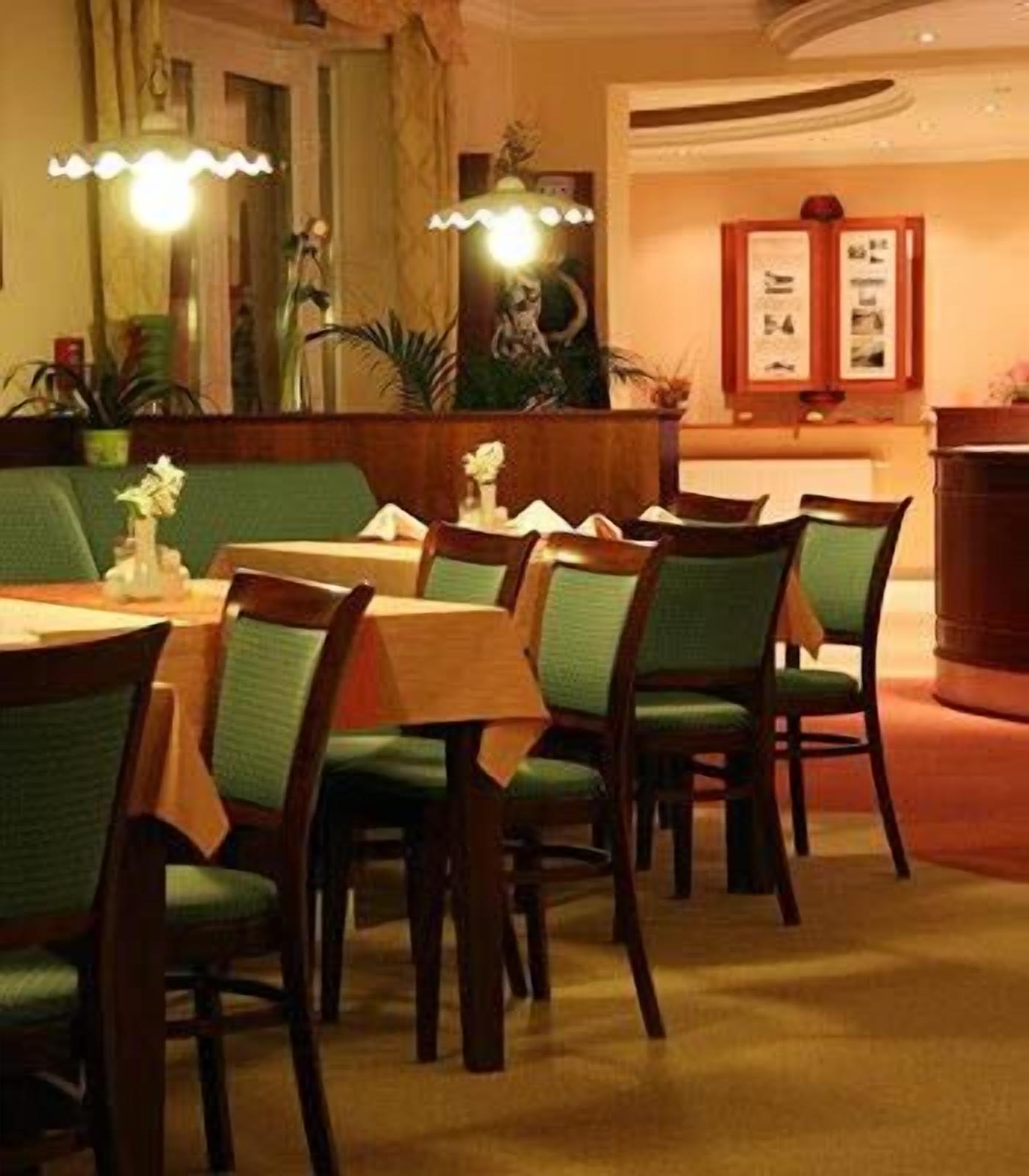 Comedor con mesas de madera y sillas tapizadas en verde.