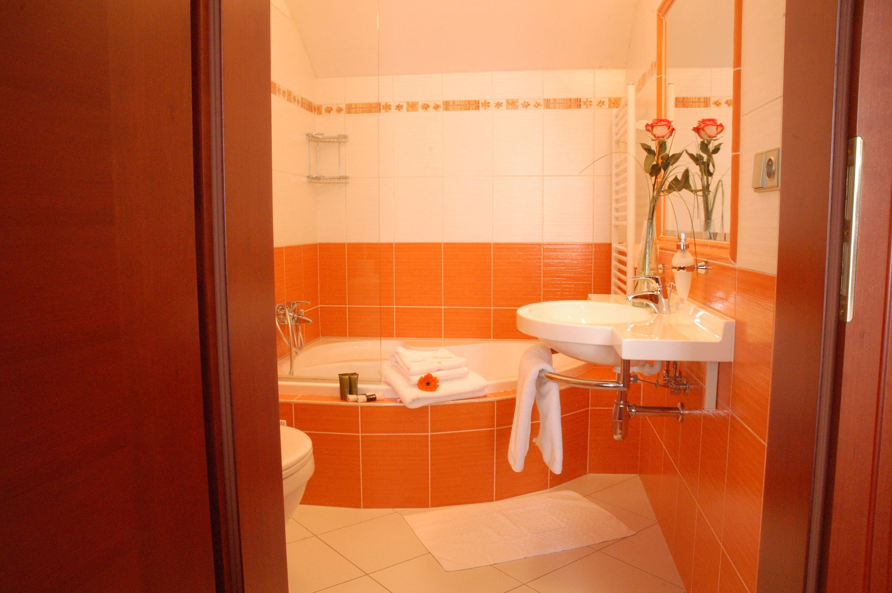 Un bagno con piastrelle arancioni e bianche, una vasca, un lavandino e uno specchio.