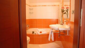 Un bagno con piastrelle arancioni e bianche, una vasca, un lavandino e uno specchio.