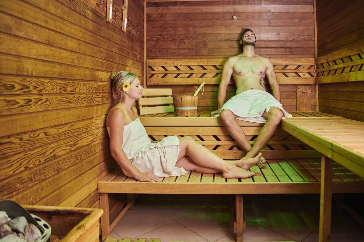 Una sauna de madera con dos bancos, uno ocupado por una persona y el otro vacío.
