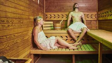 Una sauna de madera con dos bancos, uno ocupado por una persona y el otro vacío.