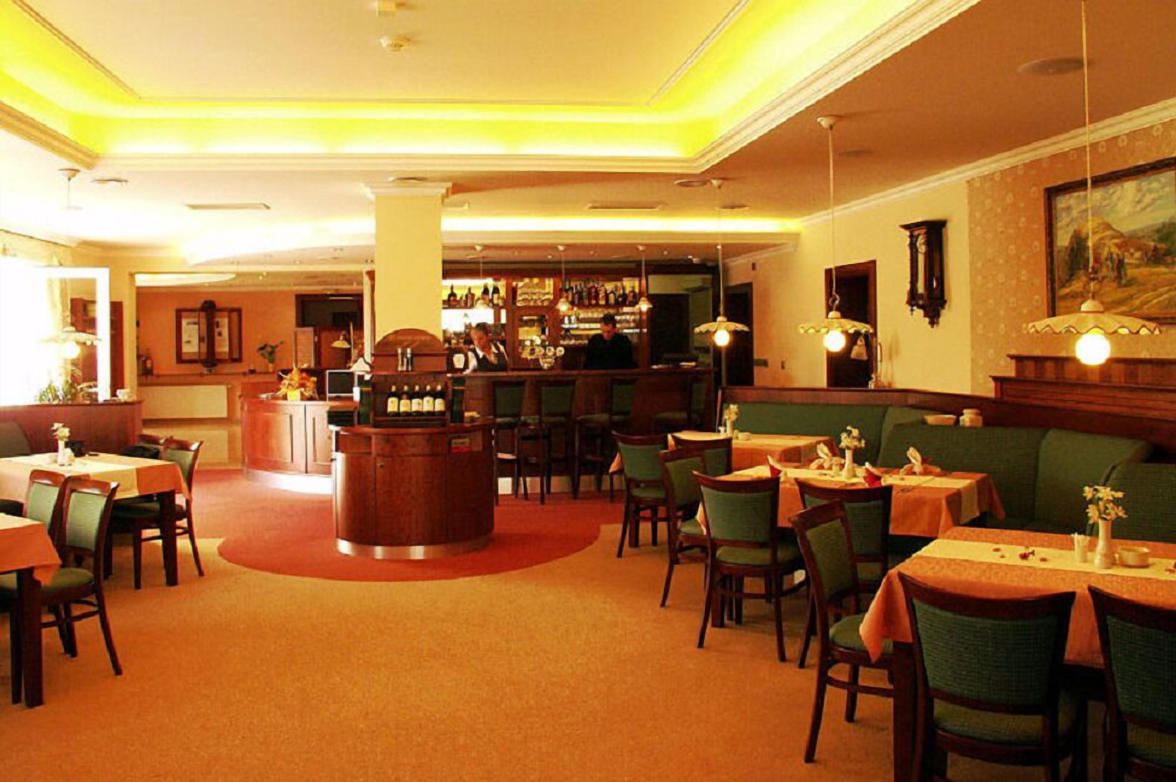 Ein Restaurant mit Bar, runden Tischen und Sitzecken.