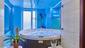 A modern bathroom with a hot tub, a potted plant, and a champagne glass. - Hotel Komorni Hurka (Cheb)