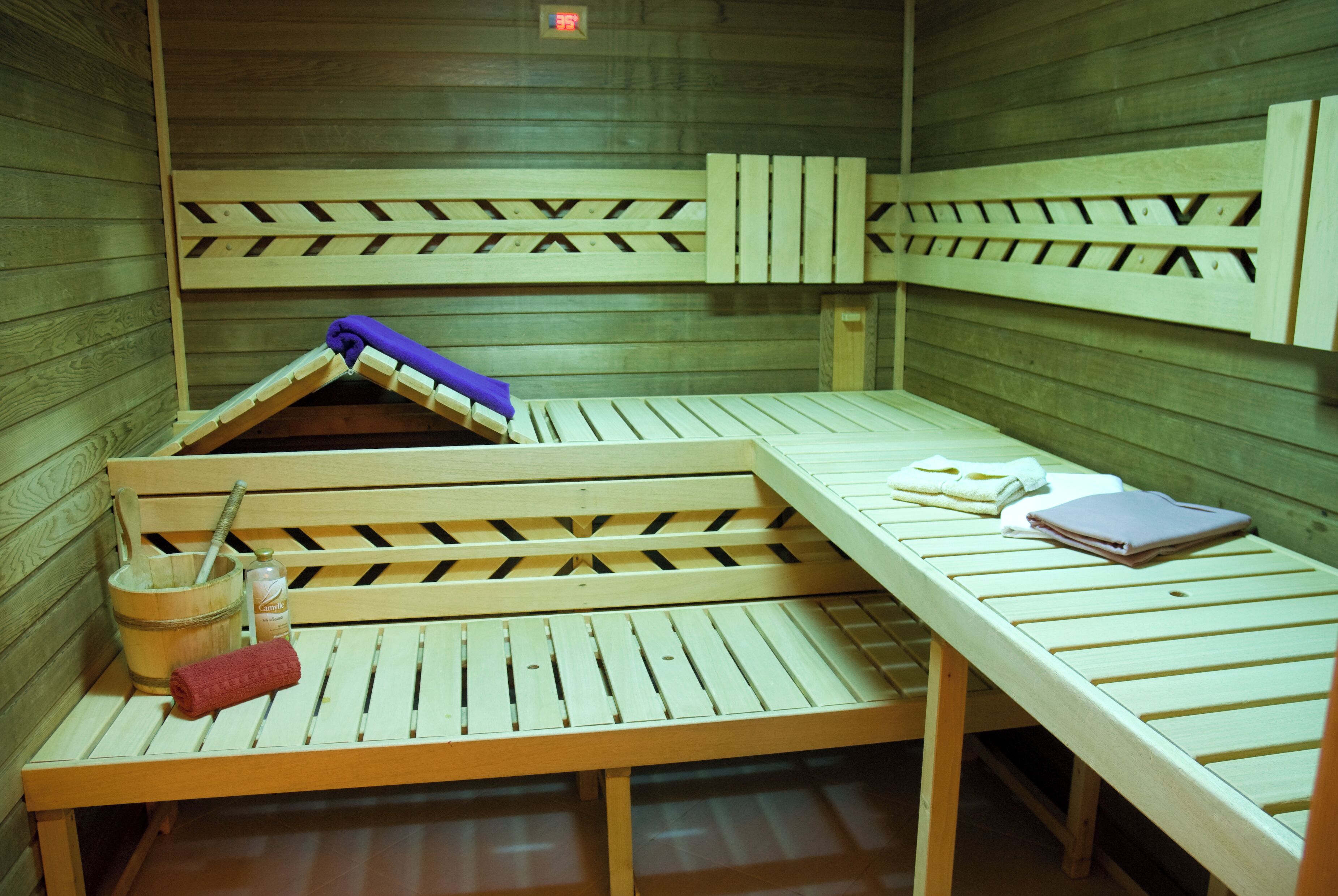 A sauna room with wooden benches and benches, a wooden bucket, and a towel.