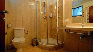 Une salle de bain comprenant des toilettes, un espace douche et un lavabo avec un miroir.