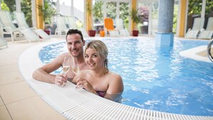 A couple in a hot tub with a view of outdoor seating and plants. - Ferienhotel Trattnig GmbH (Radenthein)