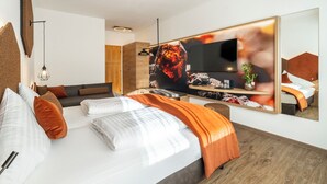 A modern bedroom with a large bed, a TV, and a mirror. - Ferienhotel Trattnig GmbH (Radenthein)