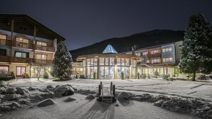 A hotel with a glass facade, multiple balconies, and a snow-covered courtyard. - Ferienhotel Trattnig GmbH (Radenthein)