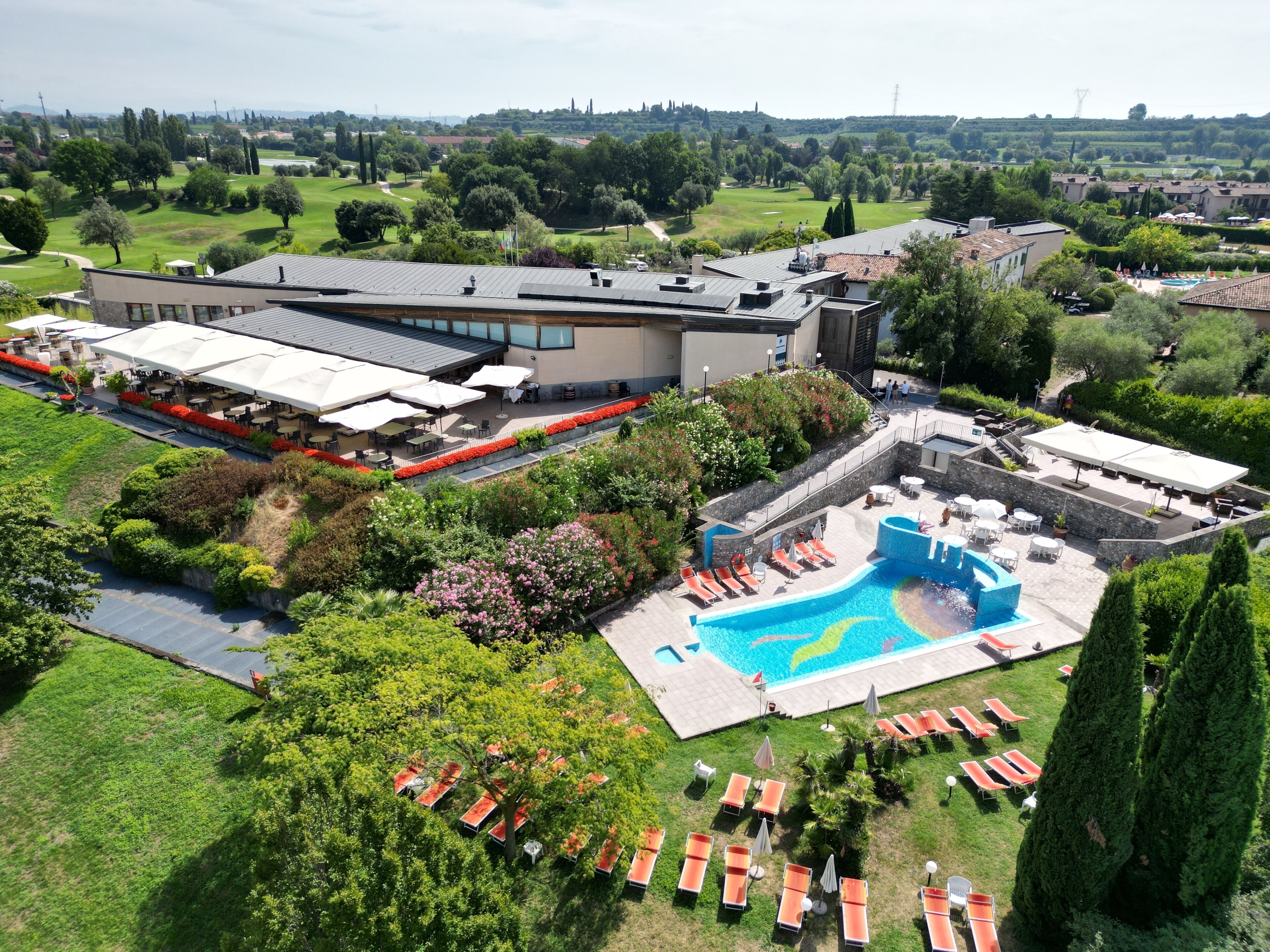 Een hotel met een zwembad, buitenterras en een golfbaan op de achtergrond.