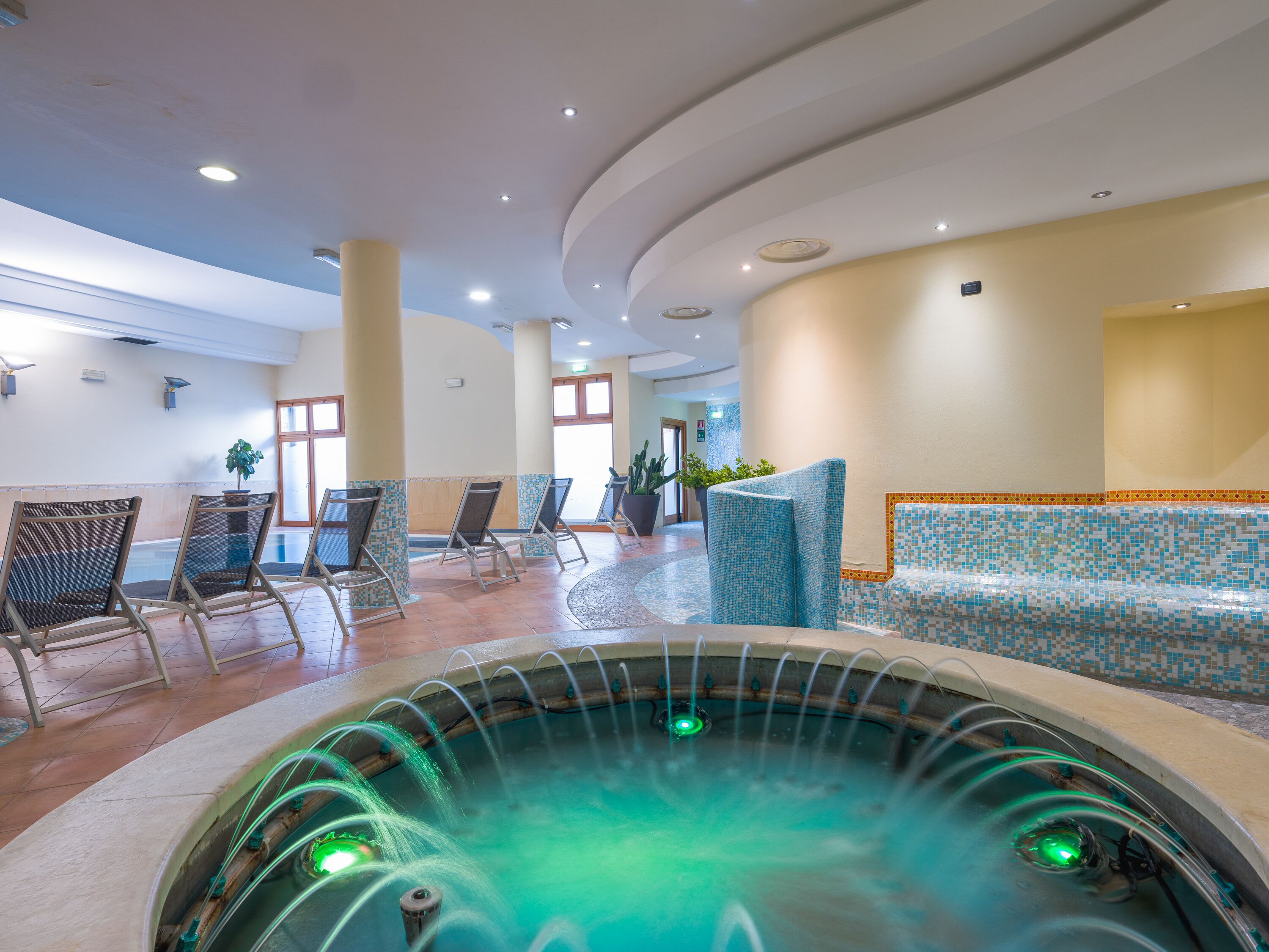Uma área de spa com hidromassagem, assentos e piso ladrilhado.
