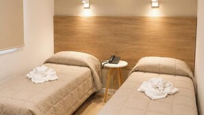 A hotel room with two beds, a small table, and two wall-mounted lights. - Milan Hotel (Buenos Aires)