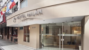 A hotel entrance with a glass facade, a sign reading "HOTEL MILAN BUENOS AIRES", and a visible address "387/335". - Milan Hotel (Buenos Aires)