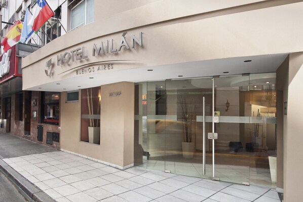 A hotel entrance with a glass facade, a sign reading "HOTEL MILAN BUENOS AIRES", and a visible address "387/335". - Milan Hotel (Buenos Aires)