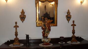 Un aparador de madera con espejo, candelabros ornamentales y una pequeña estatua.