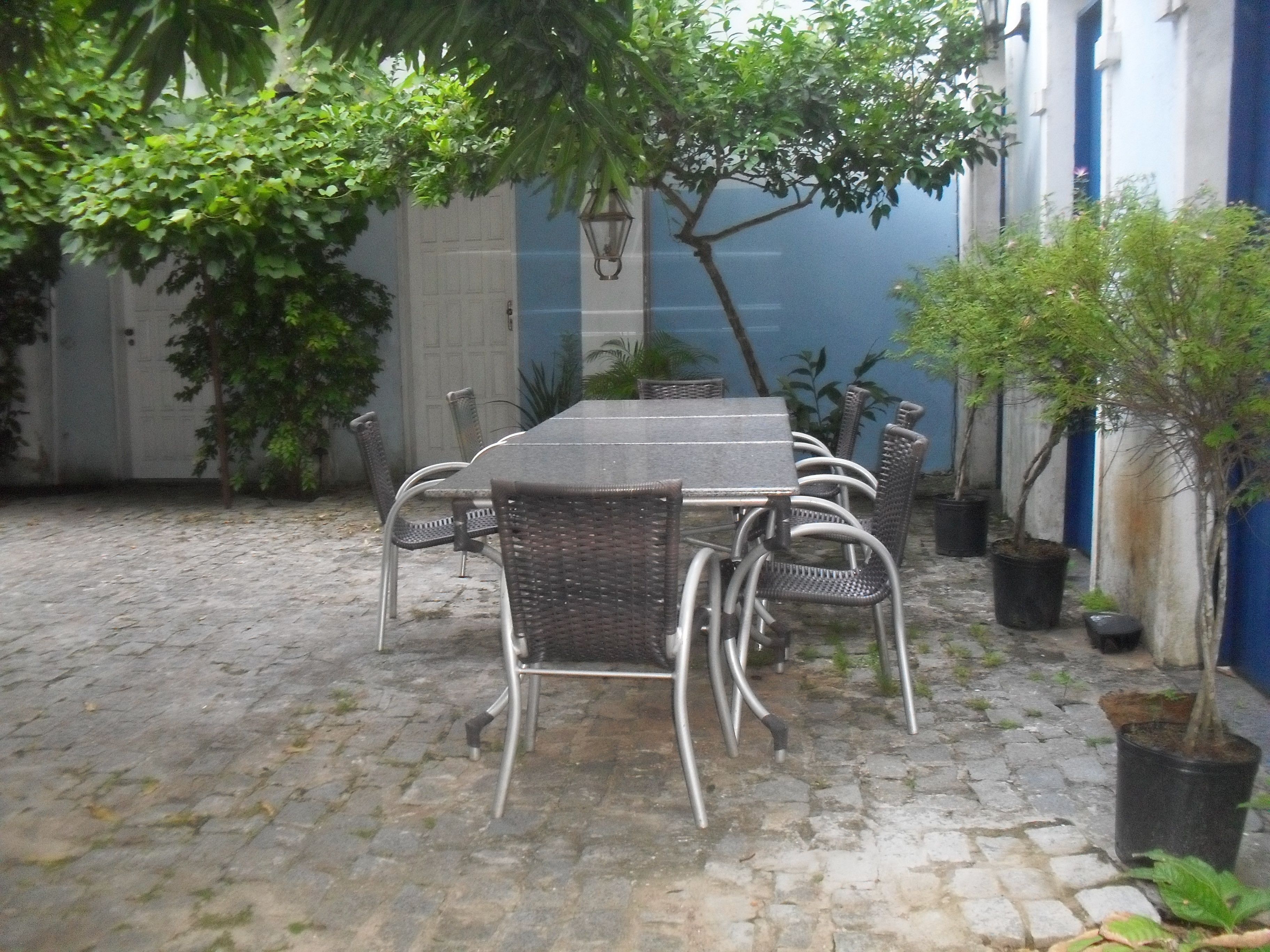Un patio con suelo de piedra, una mesa con sillas y plantas en macetas.