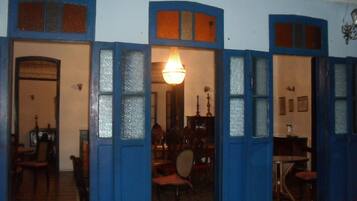 Una habitació amb una porta blava que dona a un menjador amb cadires i taula.
