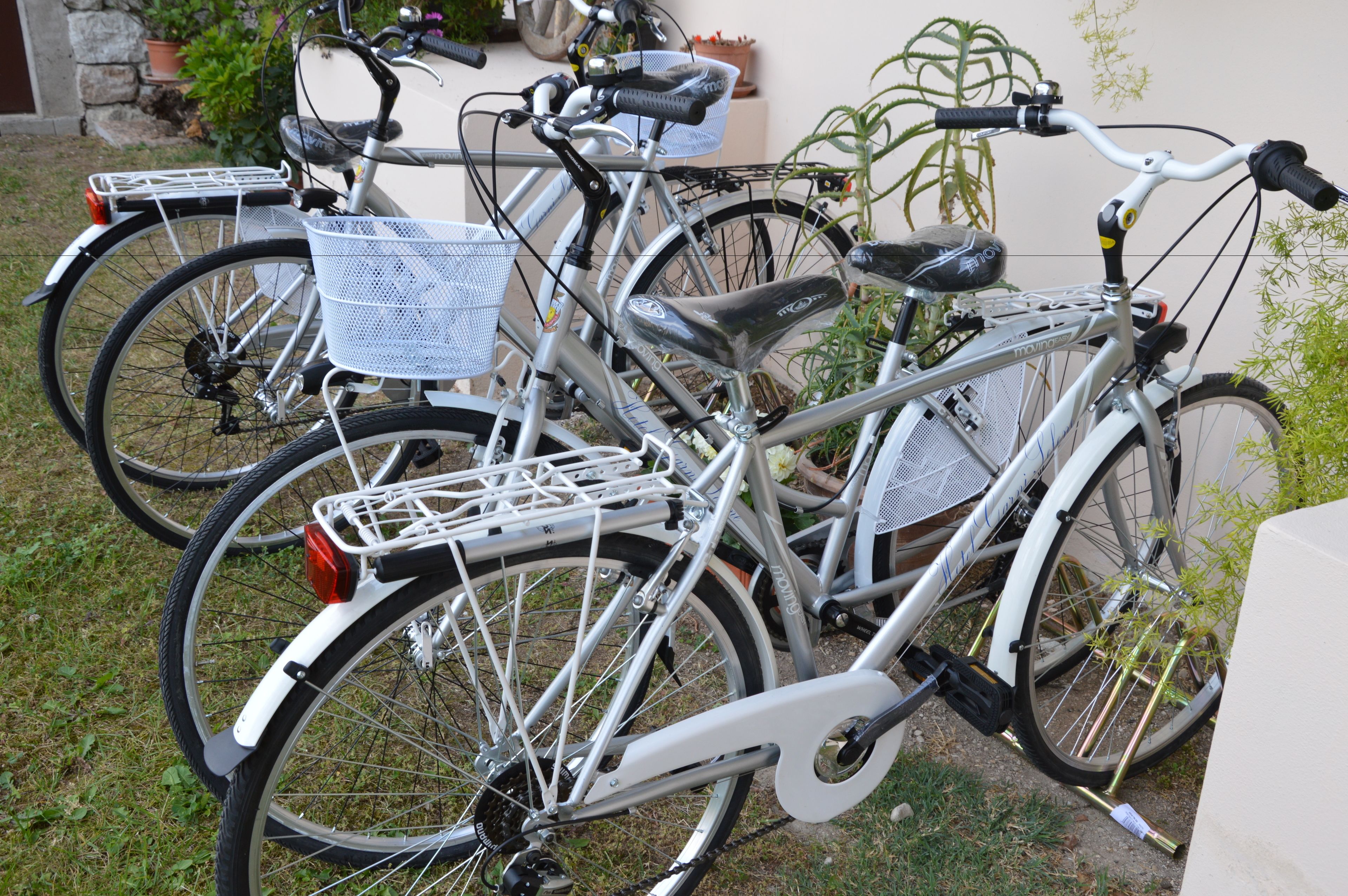 A bicycle with a basket and seat, parked on grass.