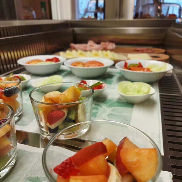 Una mesa de buffet con diversos platos, incluyendo cuencos de fruta y una zona de parrilla.