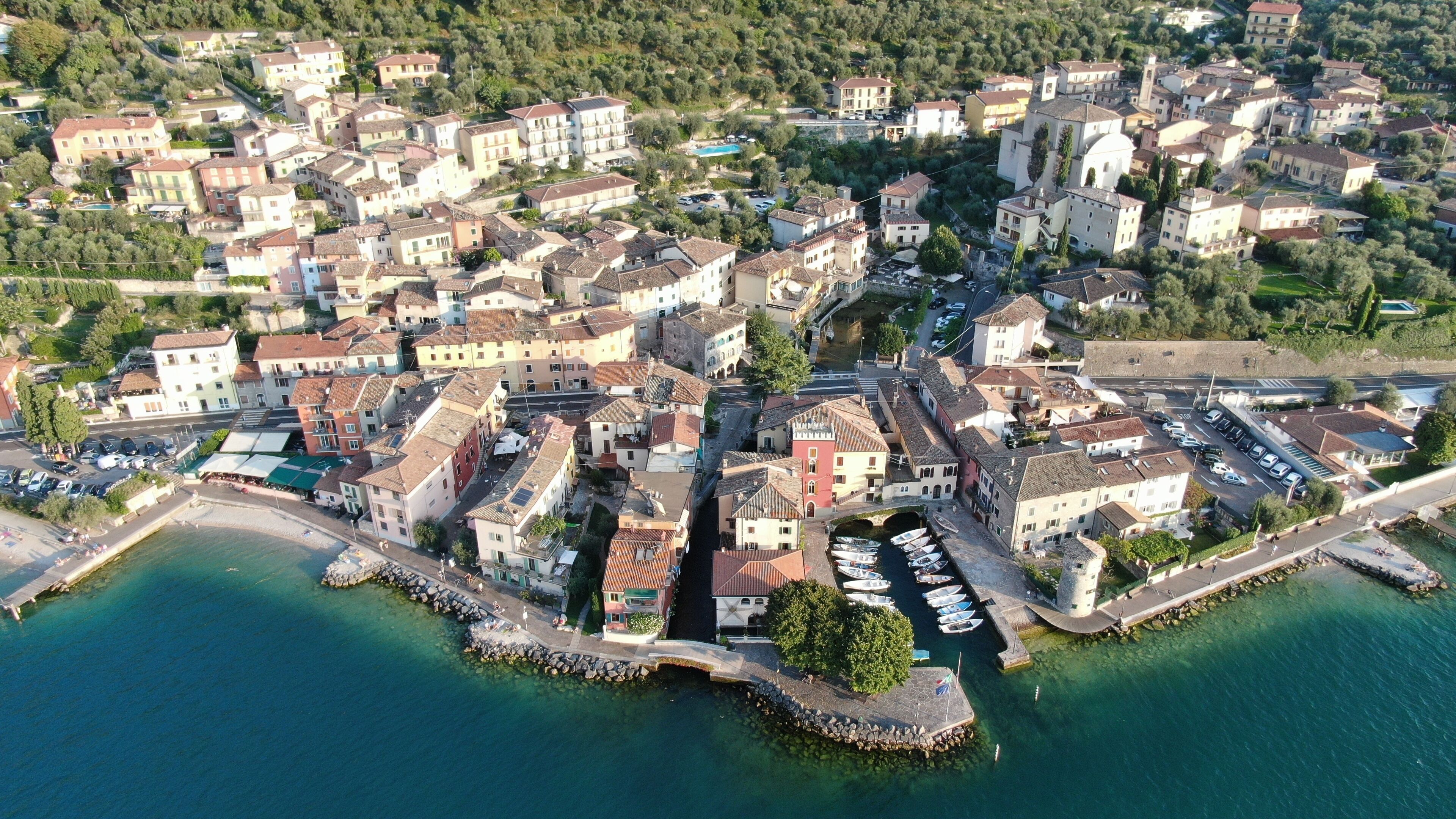 Vue aérienne d’une ville côtière, avec ses bâtiments historiques, son port de plaisance et une mer d’un bleu limpide.