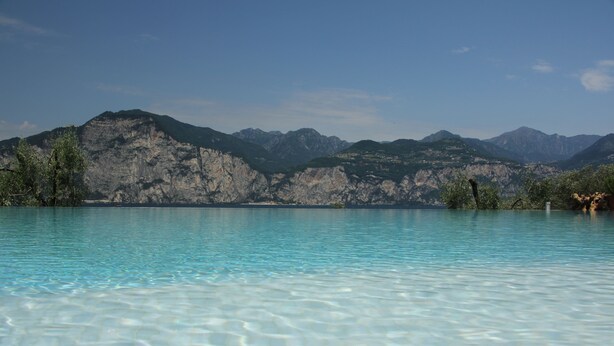 Piscina cristalina com montanhas ao fundo.