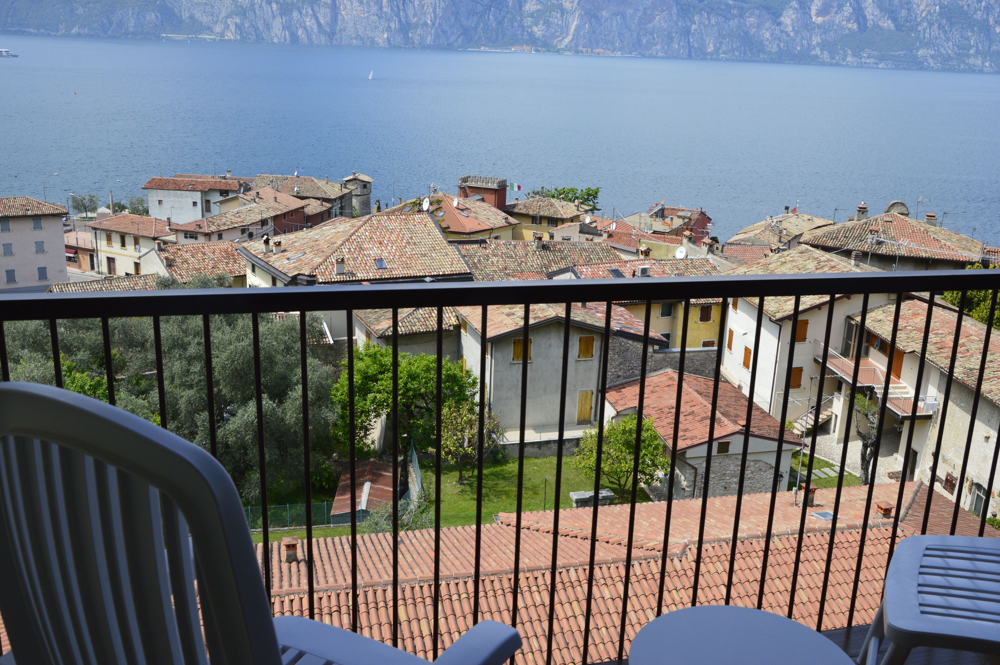 Ein Balkon mit Blick auf eine Küstenstadt, mit Häusern mit Terrakotta-Dächern und blauem Meer.