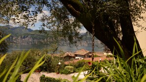 Uma vila costeira com casas tradicionais, um caminho pavimentado e vista para o mar e montanhas.