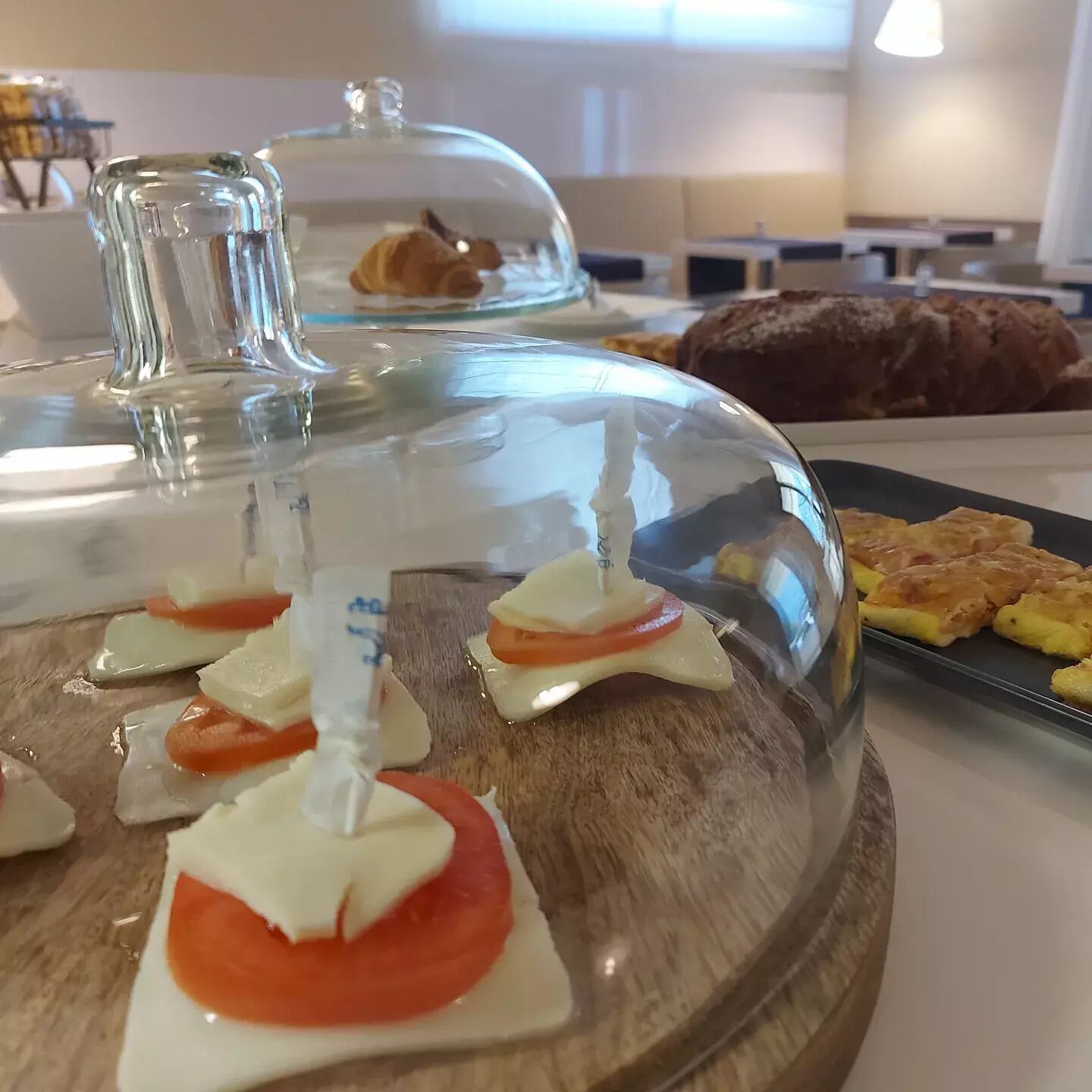 Un buffet con diversi cibi, tra cui un piatto al coperto con dolci e un vassoio con panini.
