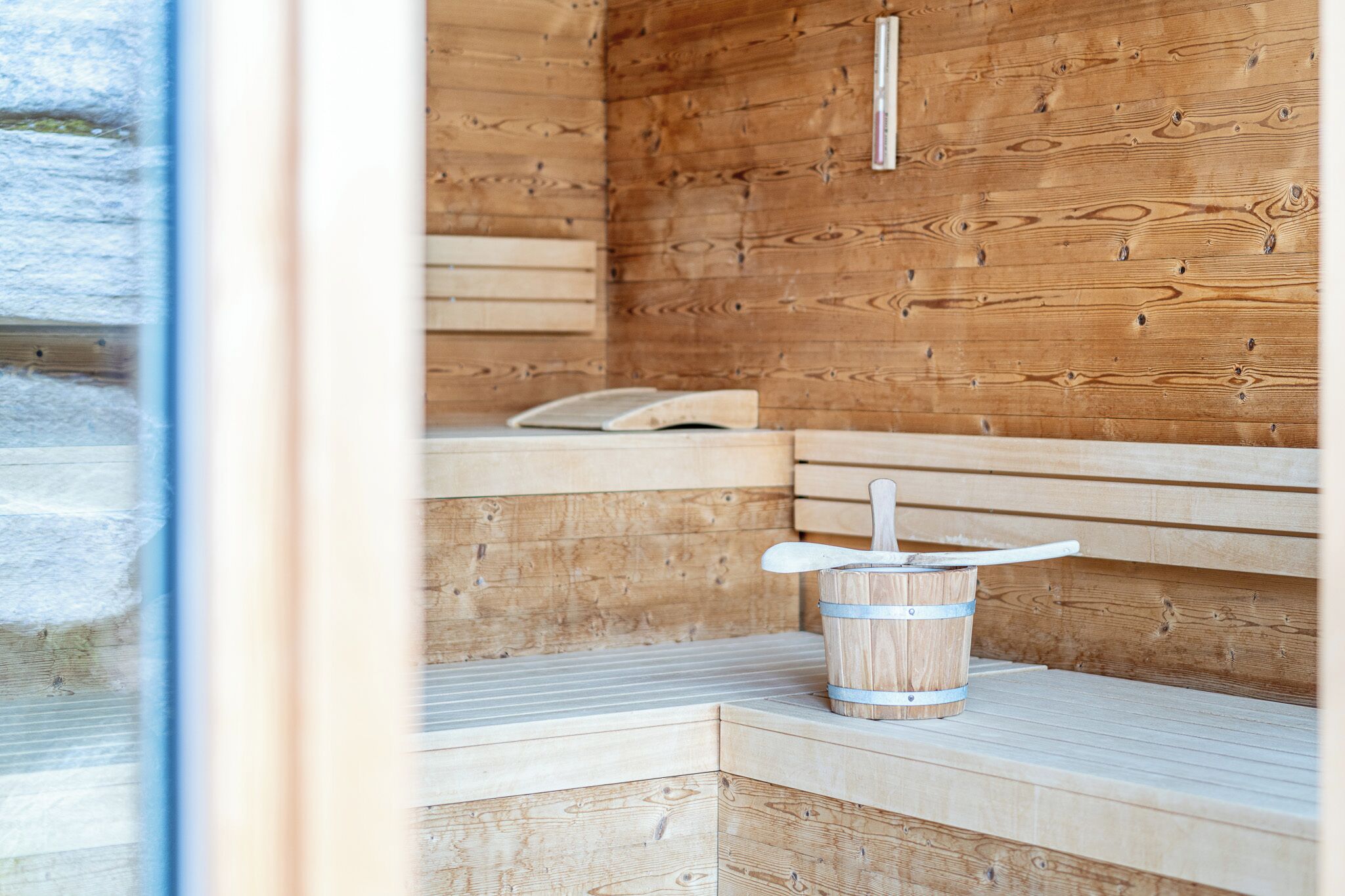 A wooden sauna with benches and a bucket.
