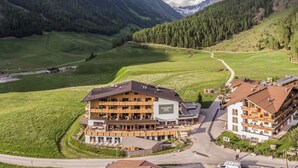 A multi-story hotel with a ski lift, surrounded by green hills and mountains. - Hotel Falknerhof (Umhausen)