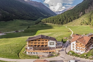 A multi-story hotel with a ski lift, surrounded by green hills and mountains. - Hotel Falknerhof (Umhausen)