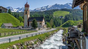 Vista de un río con una iglesia, montañas y un puente de madera.