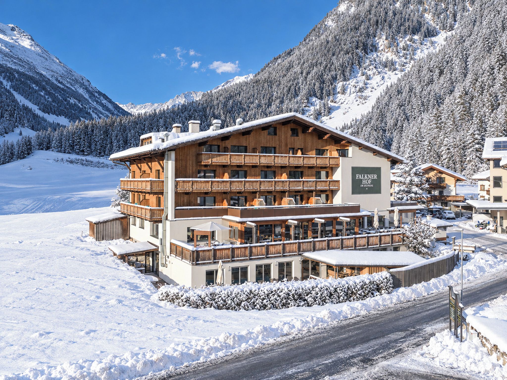 Un edificio de varios pisos con balcones, rodeado de montañas nevadas.