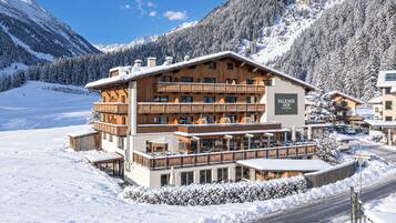 Un edificio de varios pisos con balcones, rodeado de montañas nevadas.