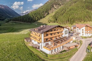 Ein mehrstöckiges Hotel mit Balkonen, im Hintergrund eine Skipiste und eine gebirgige Landschaft.