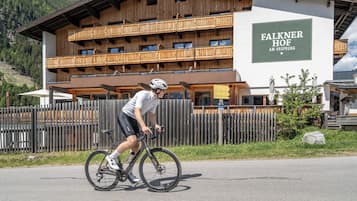 A cyclist riding past a building with a sign reading 'Falkner Hof.'