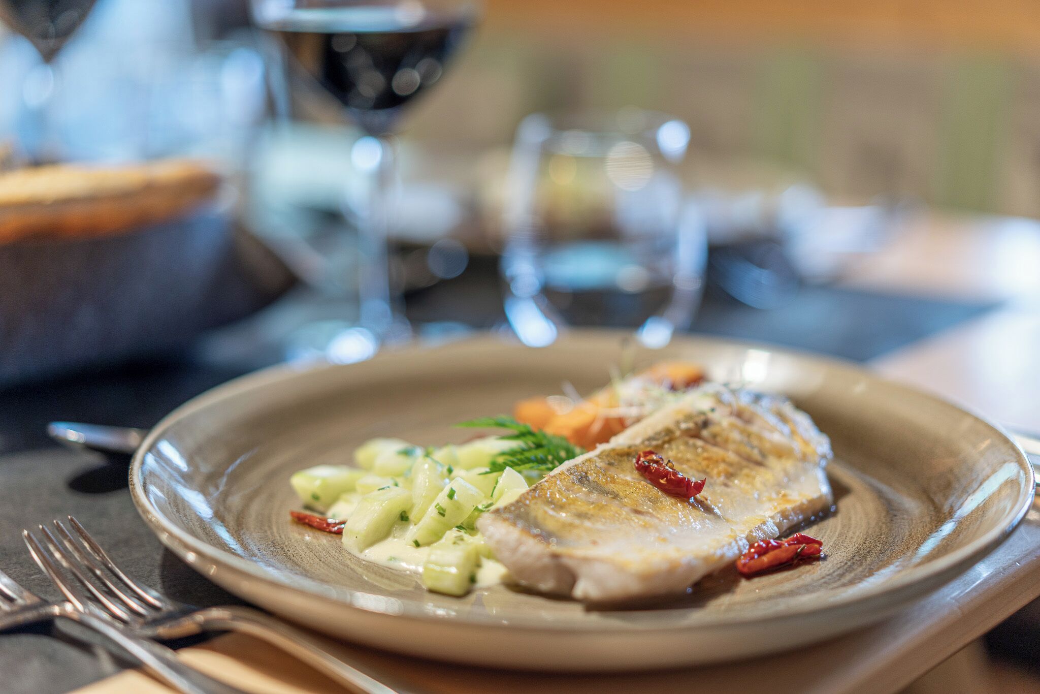 A plate with a piece of fish, vegetables, and a garnish.