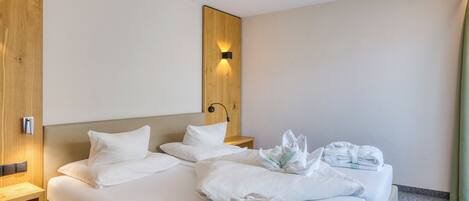 A hotel room with a bed, a wooden headboard, a nightstand, and a wall-mounted light.