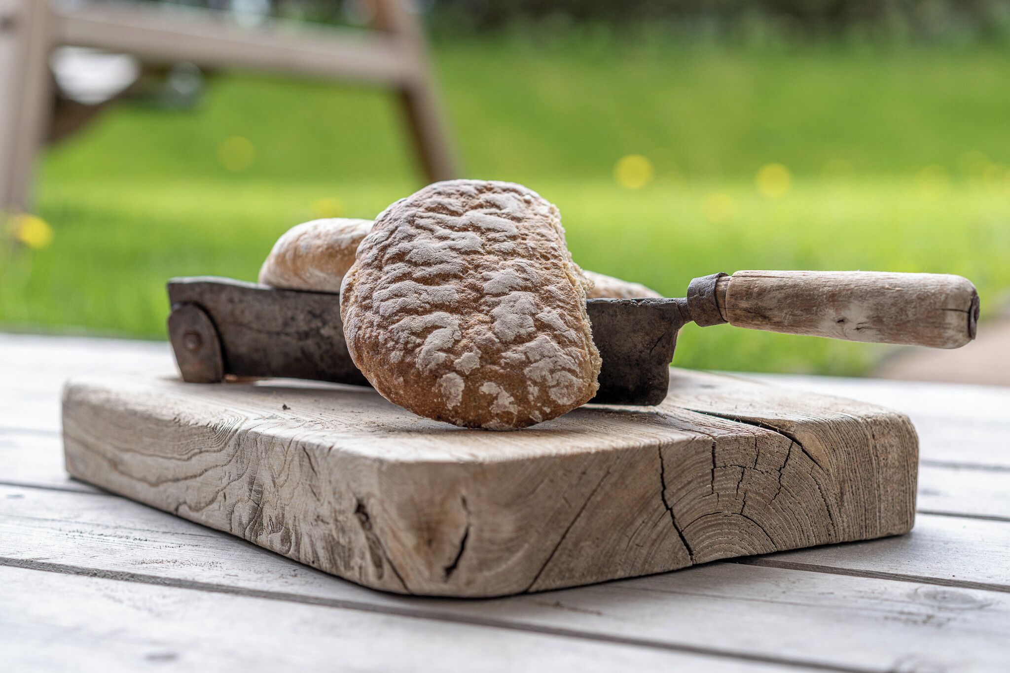 A wooden cutting board with a loaf of bread and a bread knife on it.