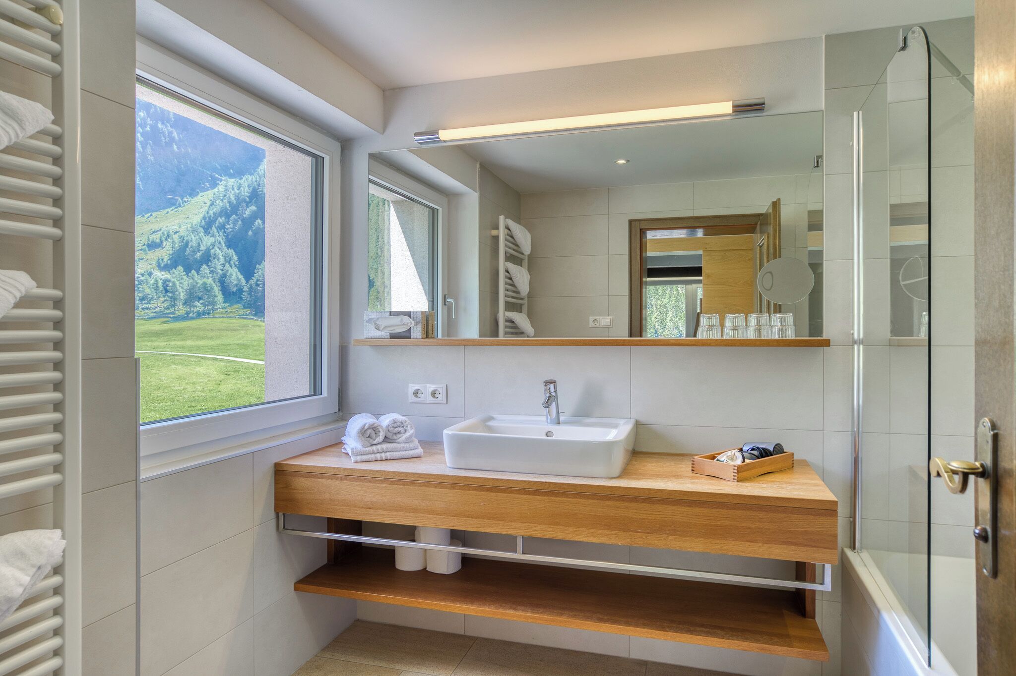 Une salle de bain moderne avec une grande fenêtre, un lavabo, un miroir et une douche.