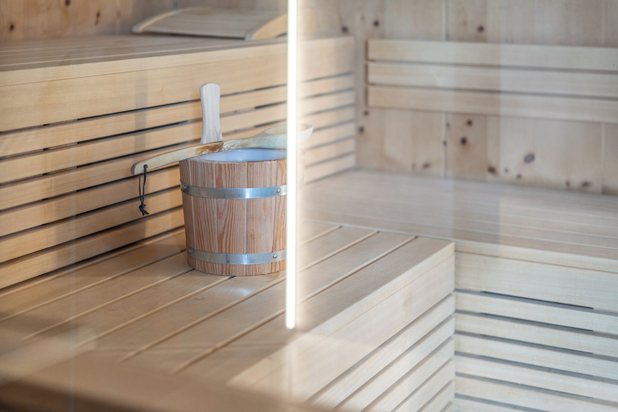 A wooden sauna bench with a towel and a wooden bucket.