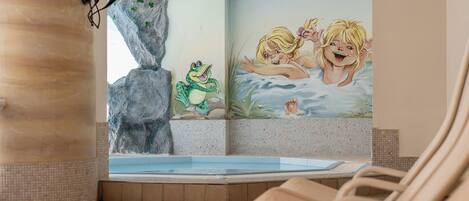 Un espacio de spa con un mural, una bañera de hidromasaje y sillones de descanso.