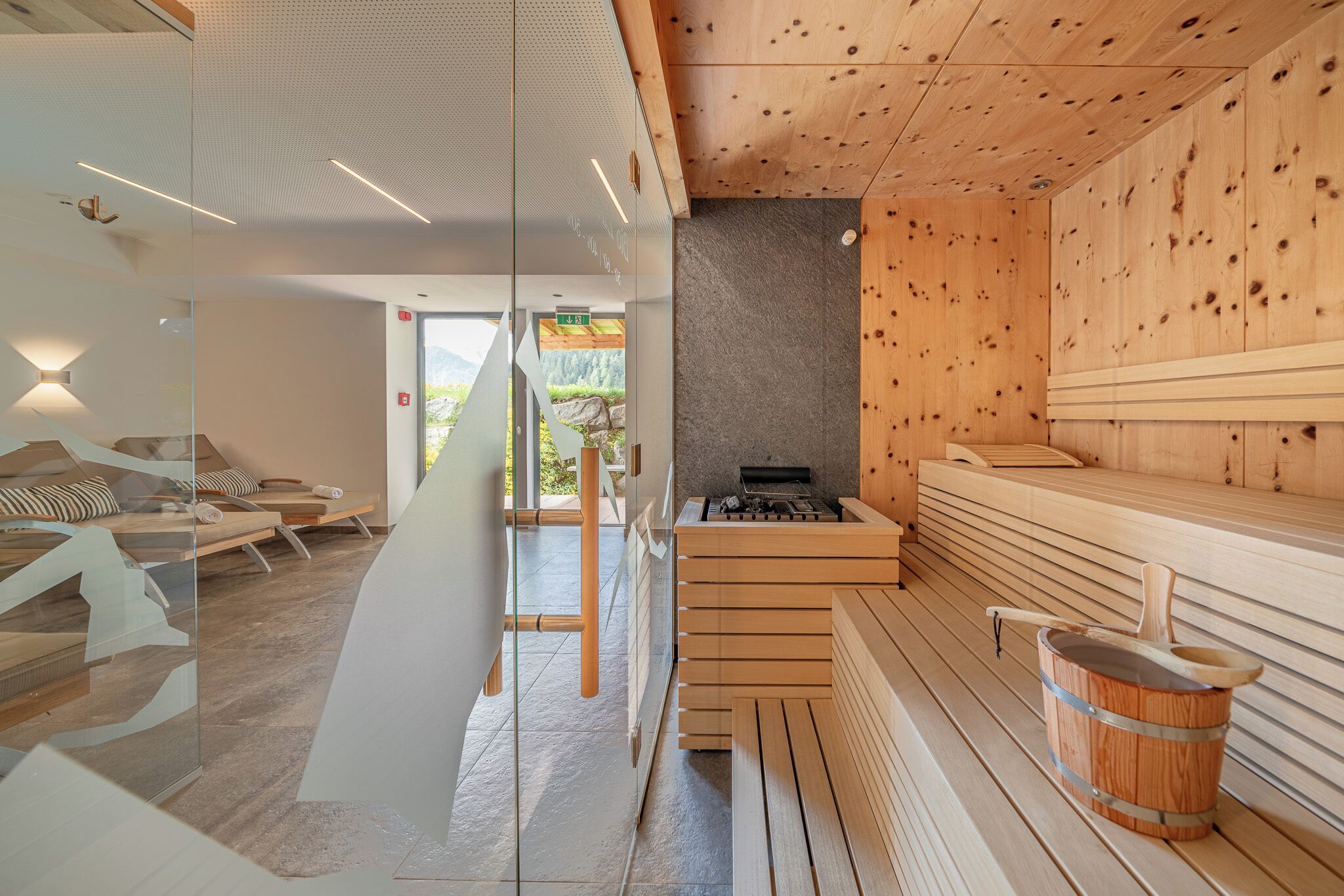 Una sala de sauna con bancos de madera, pared de piedra y calentador de sauna.
