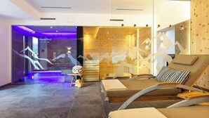 A modern interior with a reception area, a lounge with a wooden bench and cushions, and a wall with abstract art. - Hotel Falknerhof (Umhausen)