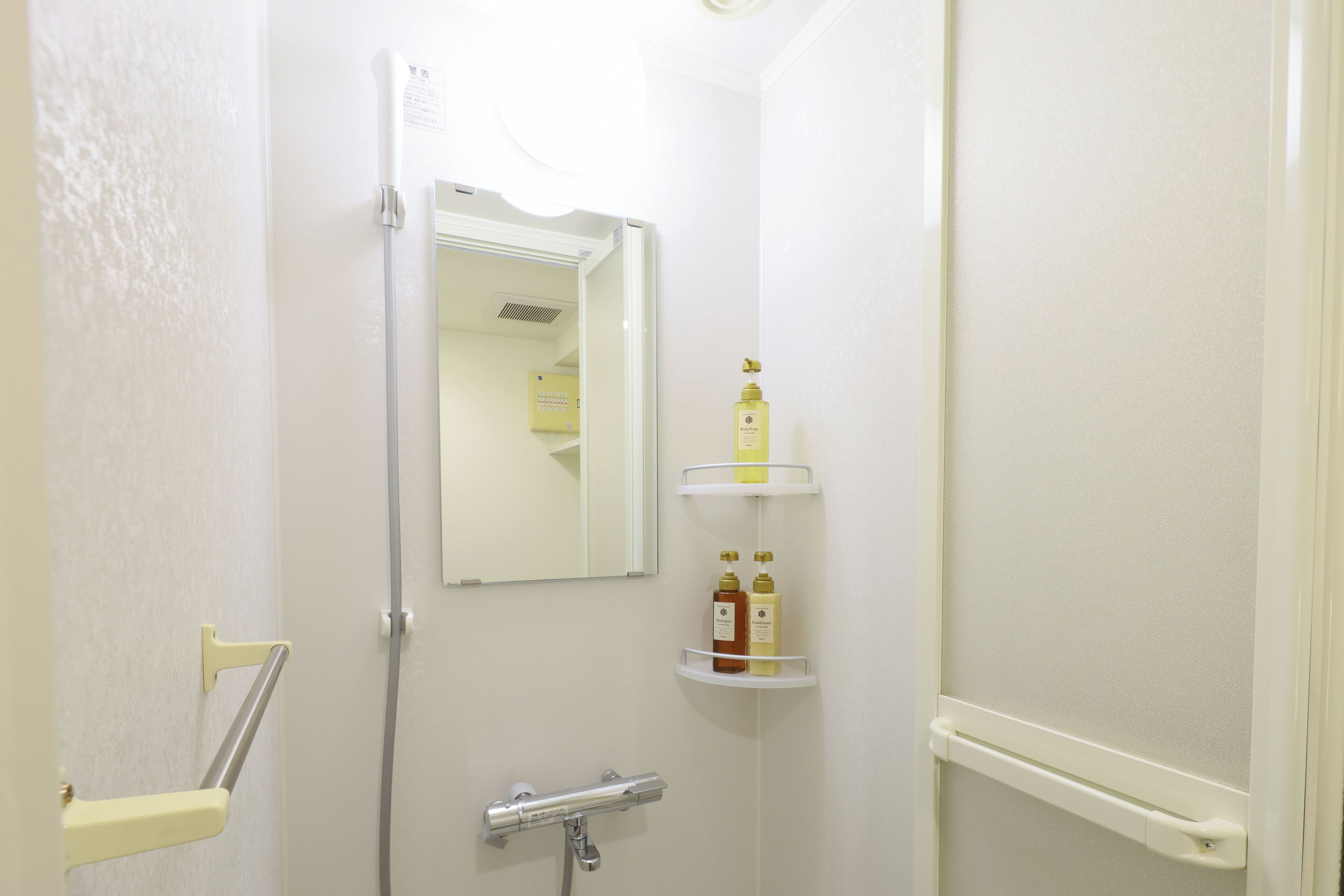 Une salle de bain avec une douche, un miroir et des étagères contenant des articles de toilette.