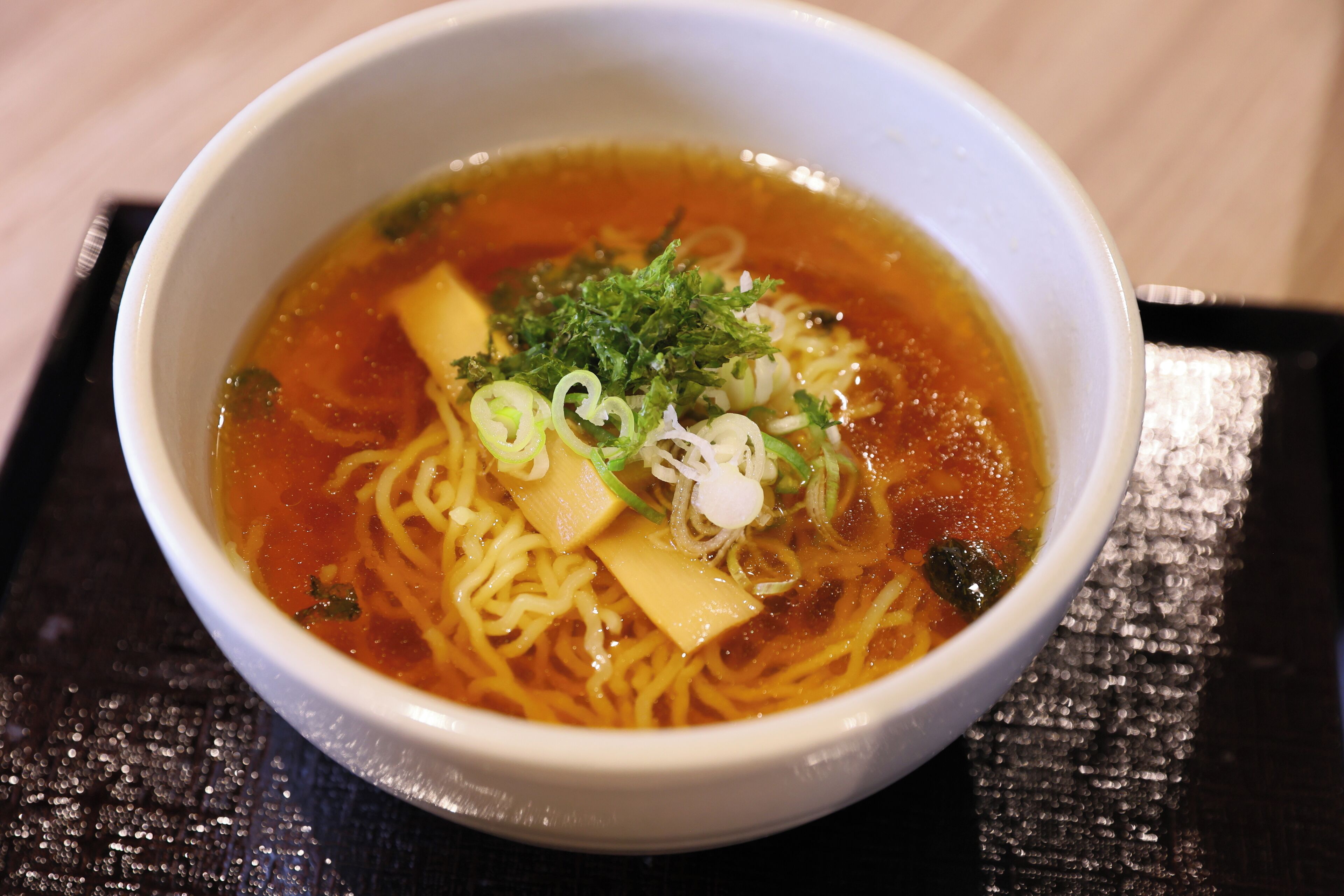A bowl of ramen with noodles, broth, tofu, and garnishes.