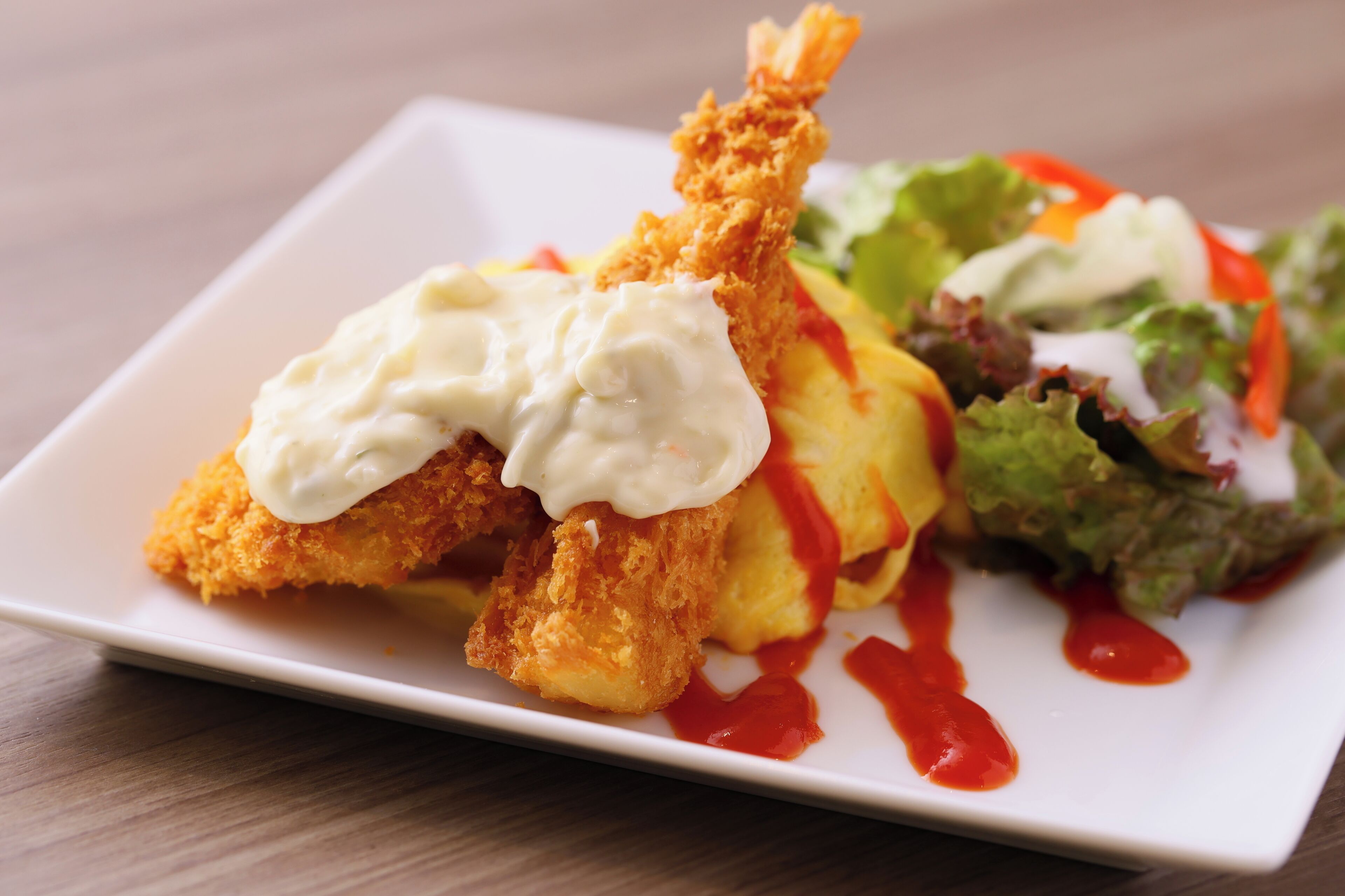 Une assiette de nourriture comprenant des aliments frits, une salade et une sauce crémeuse.