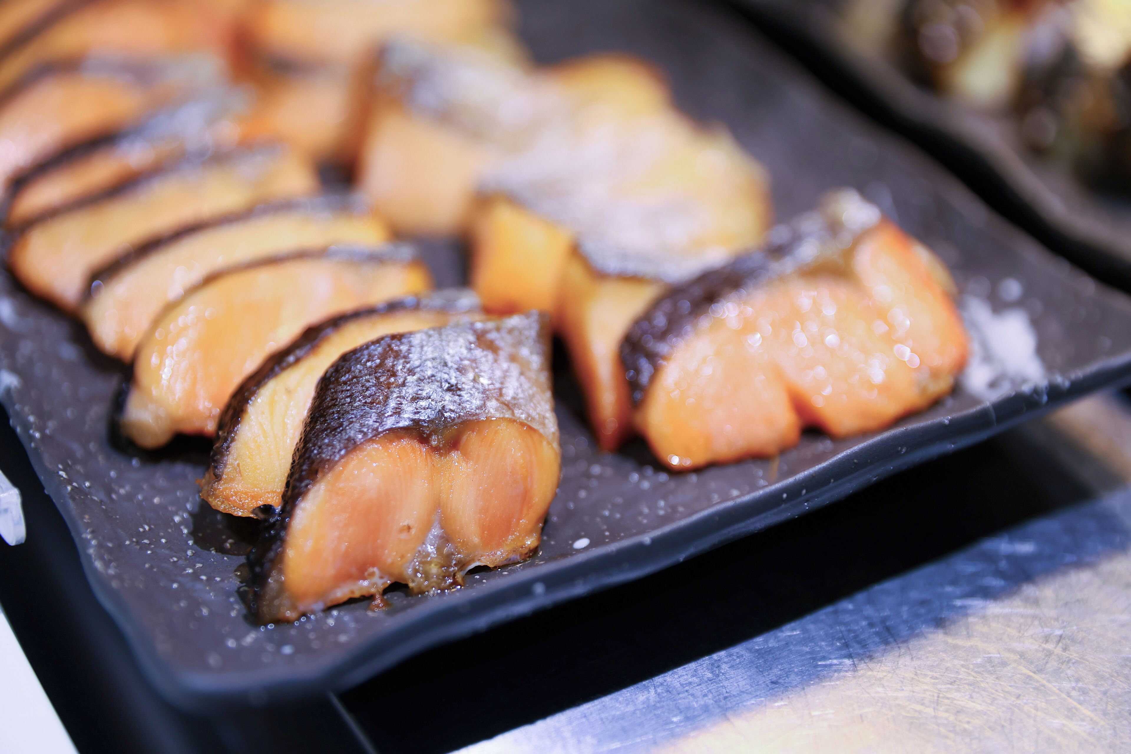 A tray of sliced salmon on a black plate.